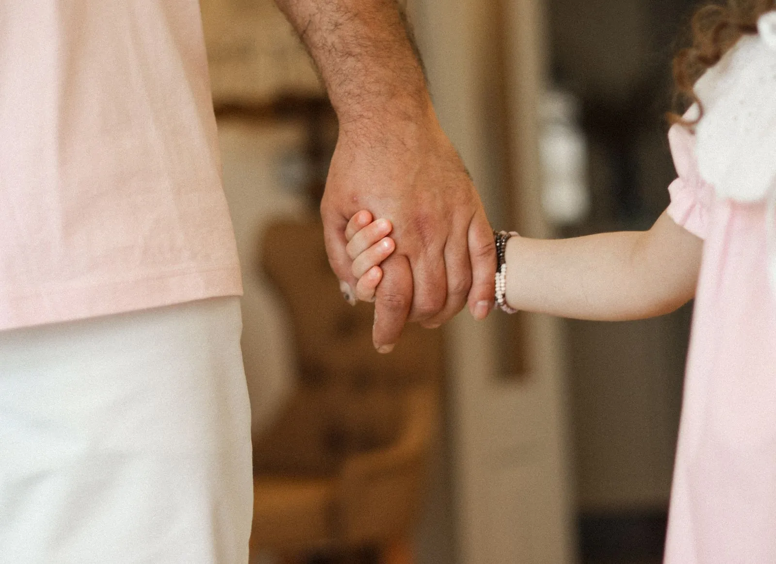 A little girl holding her father’s hand
