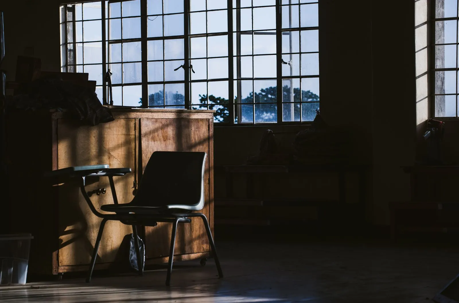 An empty chair in a quiet, dim room beside tall windows