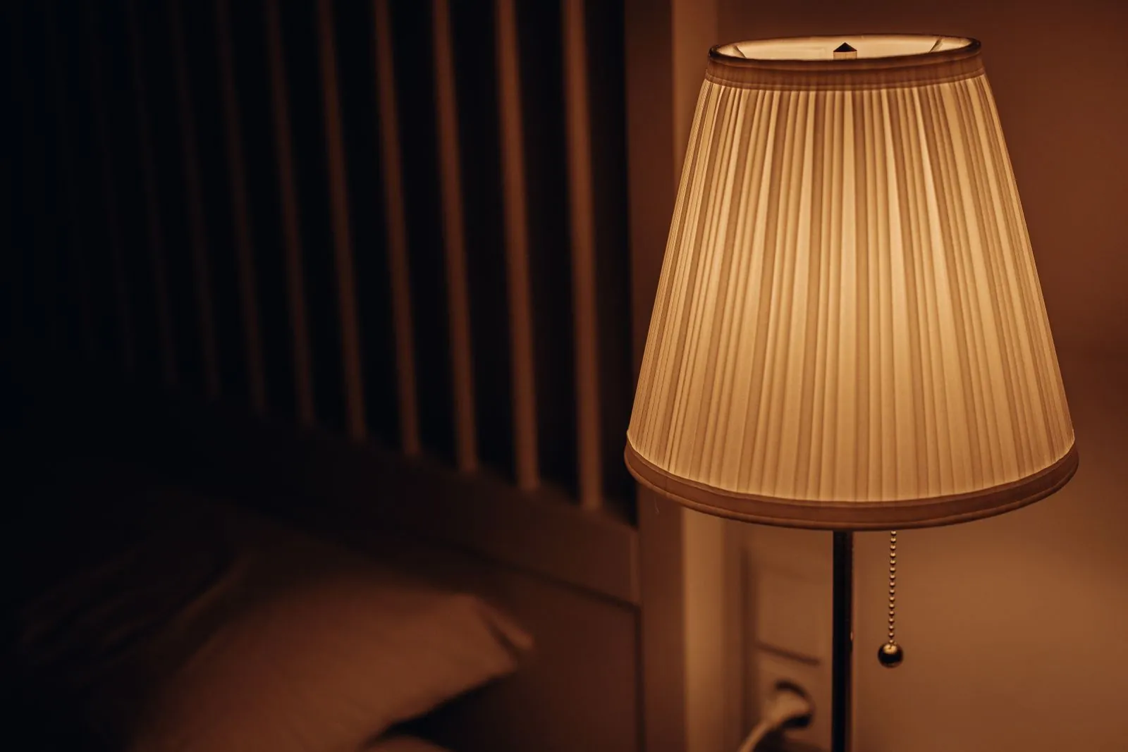 A bedside lamp glowing in a dark bedroom at night
