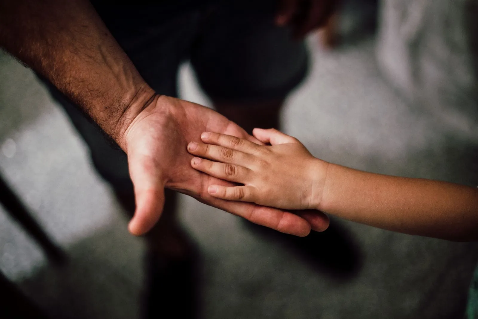 A child’s hand resting in the open palm of a man’s hand